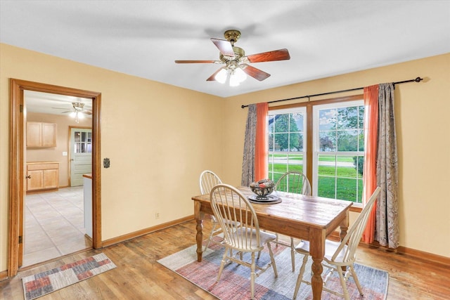 dining area featuring a ceiling fan, baseboards, and light wood-style floors