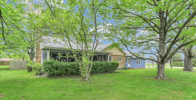 exterior space with a lawn, fence, a chimney, and a sunroom