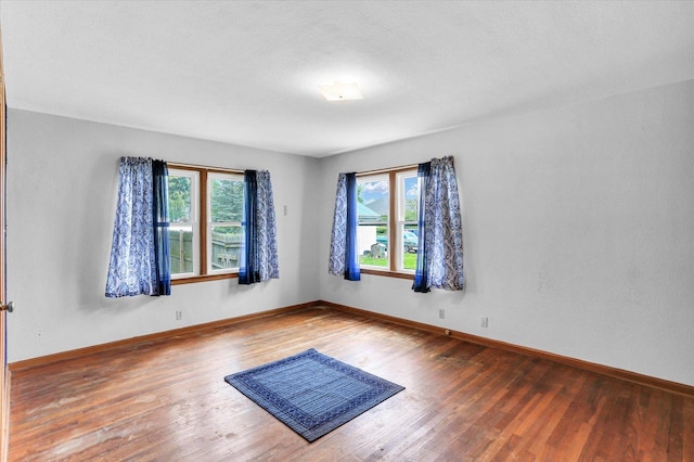 unfurnished room with baseboards, a healthy amount of sunlight, and wood finished floors