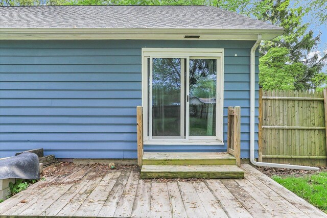 exterior space featuring fence, a downspout, gutters, and roof with shingles