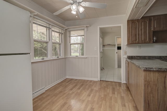 kitchen with dark countertops, baseboard heating, light wood-style floors, freestanding refrigerator, and a ceiling fan