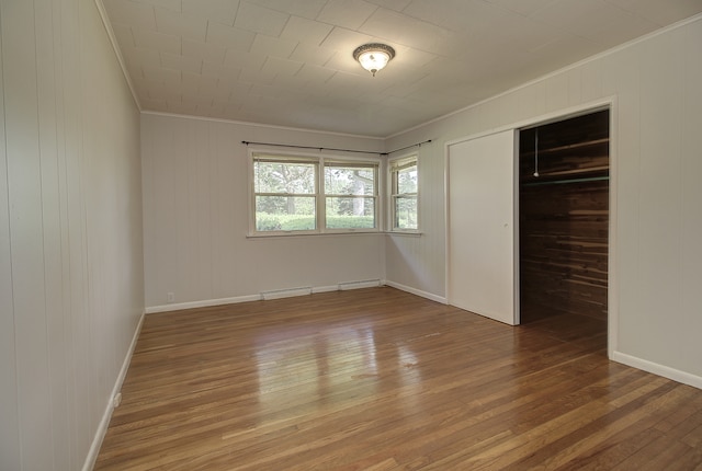 14521 S Naperville Rd, Plainfield, IL 60544 - unfurnished bedroom with crown molding, wood-type flooring, a closet, a baseboard radiator, and wooden walls
