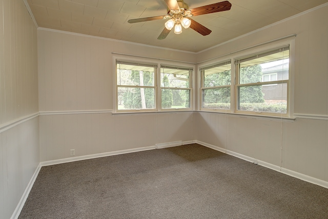 empty room with crown molding, a ceiling fan, dark colored carpet, and visible vents