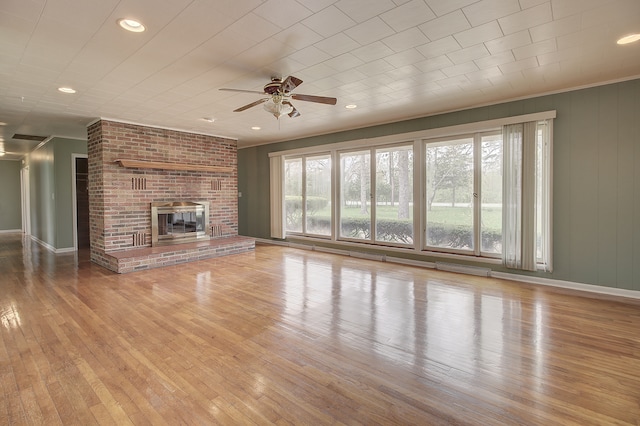 unfurnished living room with baseboards, ceiling fan, a brick fireplace, and hardwood / wood-style floors