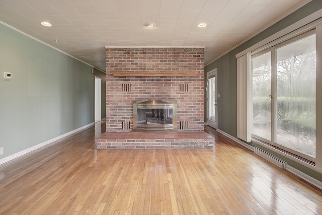 unfurnished living room featuring crown molding, baseboards, a brick fireplace, and hardwood / wood-style flooring