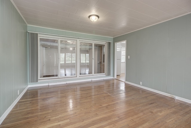 empty room with baseboards, ornamental molding, and wood-type flooring