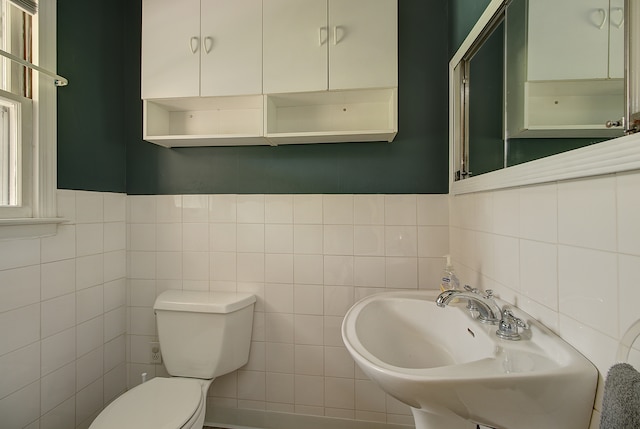 bathroom featuring a sink, toilet, and tile walls