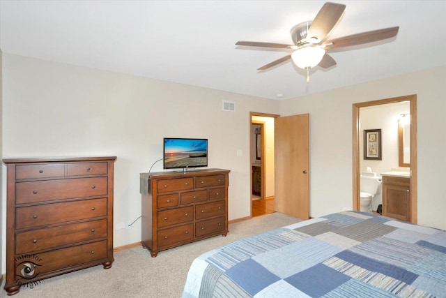 bedroom featuring light carpet, ensuite bath, baseboards, and a ceiling fan