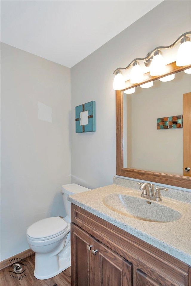 bathroom with toilet, vanity, and wood finished floors