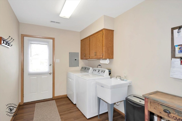 washroom featuring cabinet space, electric panel, wood finished floors, and washing machine and dryer