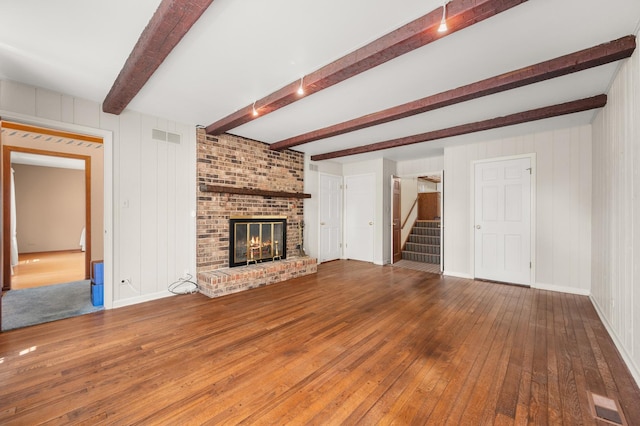 726 Parkside Dr, Sycamore, IL 60178 - unfurnished living room featuring wood-type flooring, stairway, a fireplace, beam ceiling, and baseboards