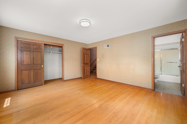 726 Parkside Dr, Sycamore, IL 60178 - unfurnished bedroom with wallpapered walls, light wood finished floors, a closet, baseboards, and ensuite bath