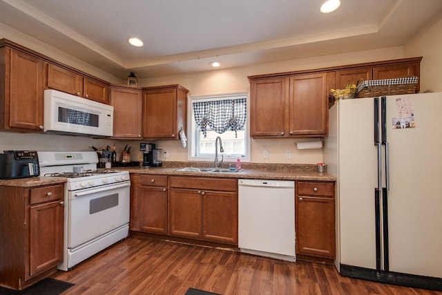 kitchen featuring white appliances, brown cabinets, dark wood-style floors, and a sink