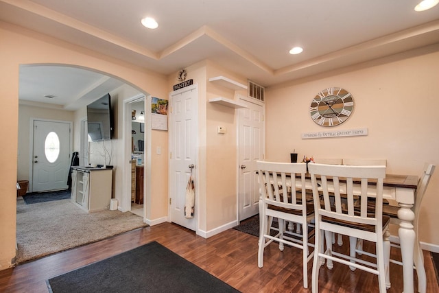 dining room featuring visible vents, arched walkways, baseboards, and wood finished floors