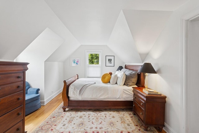 bedroom featuring vaulted ceiling, baseboards, and light wood-type flooring