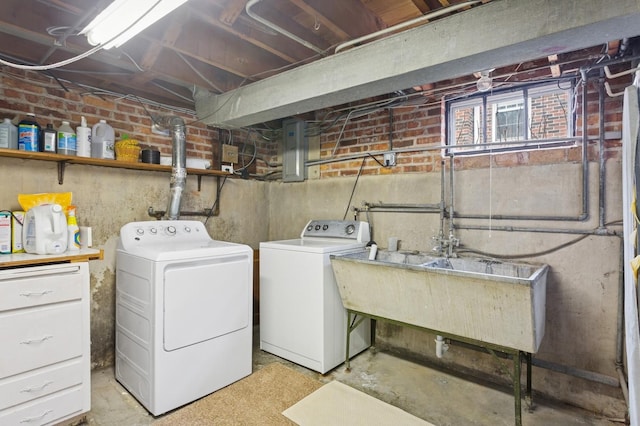 laundry area featuring electric panel, laundry area, washing machine and dryer, and brick wall