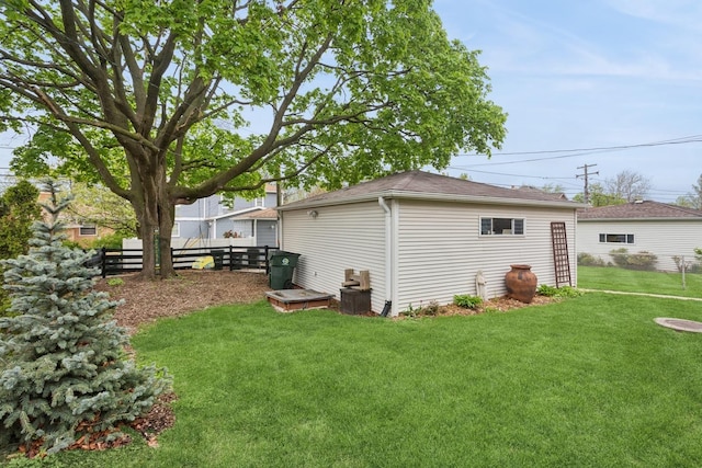 exterior space with fence, a shingled roof, and a lawn
