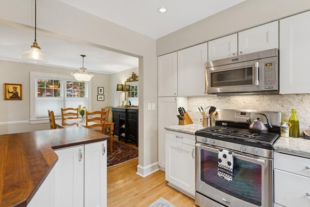 kitchen with backsplash, stainless steel appliances, butcher block counters, and a notable chandelier