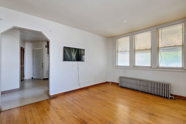 2335 N Merrimac Ave, Chicago, IL 60639 - spare room with radiator, baseboards, arched walkways, and light wood-style floors