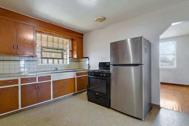 2335 N Merrimac Ave, Chicago, IL 60639 - kitchen featuring freestanding refrigerator, black gas range, baseboards, decorative backsplash, and light countertops