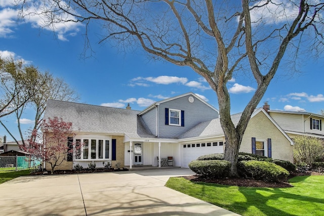 traditional-style home with a garage, a front lawn, a chimney, and concrete driveway