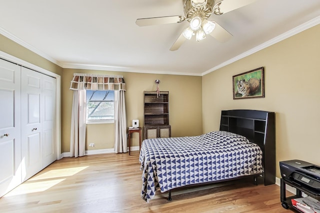 bedroom featuring light wood-style floors, ornamental molding, ceiling fan, and a closet