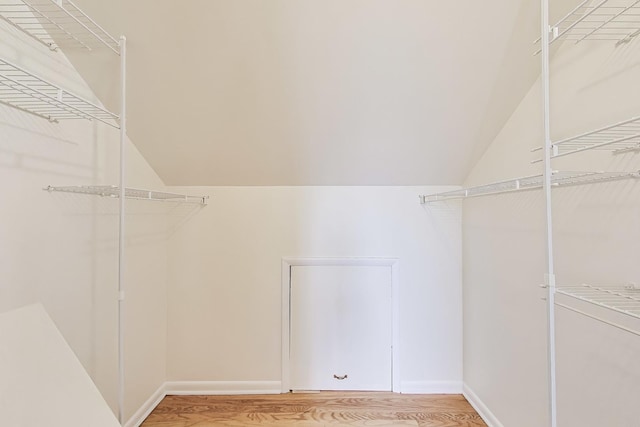 walk in closet with light wood-type flooring and lofted ceiling