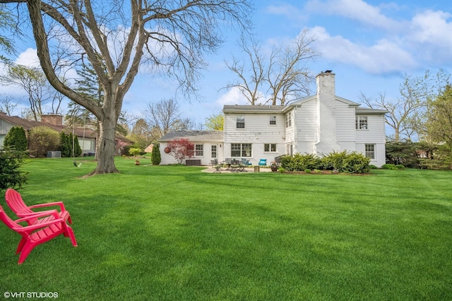 back of property featuring a yard, a chimney, and a patio