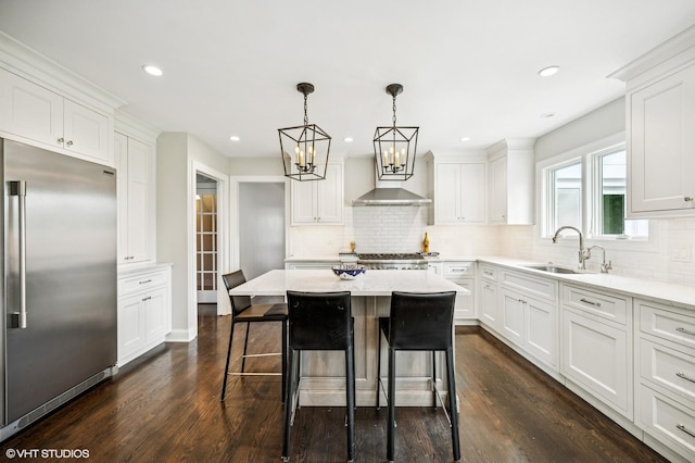 kitchen with white cabinetry, dark wood finished floors, built in fridge, and a sink