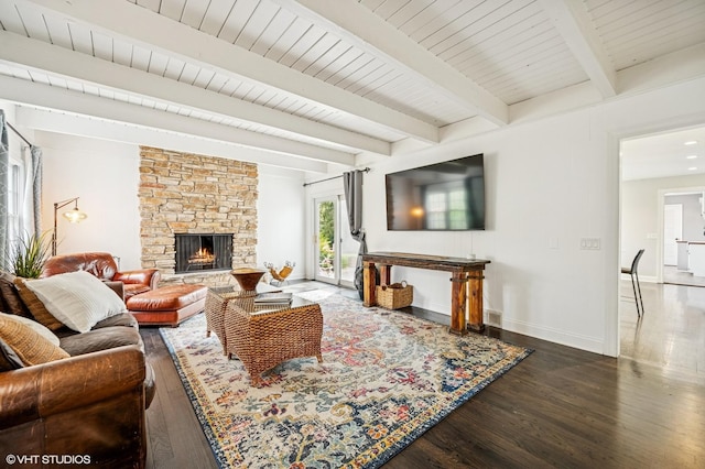 living area with a fireplace, beamed ceiling, baseboards, and wood finished floors
