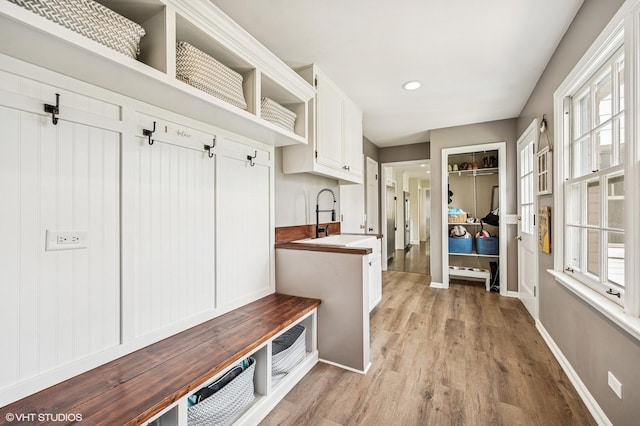 mudroom with a sink, light wood-style flooring, baseboards, and recessed lighting