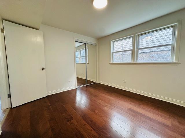unfurnished bedroom with dark wood-type flooring, baseboards, and a closet
