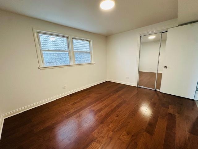 unfurnished bedroom featuring a closet, baseboards, and dark wood-type flooring