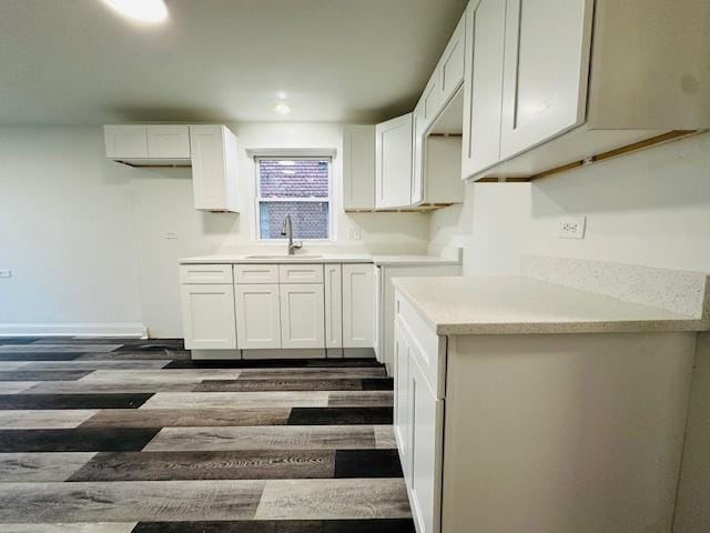 kitchen with dark wood-type flooring, recessed lighting, light countertops, white cabinets, and a sink