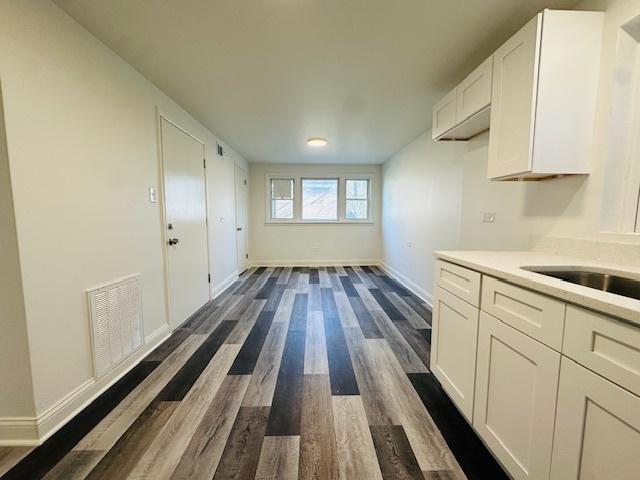 interior space featuring light countertops, dark wood finished floors, white cabinetry, baseboards, and visible vents