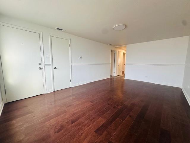 empty room with baseboards, wood finished floors, and visible vents
