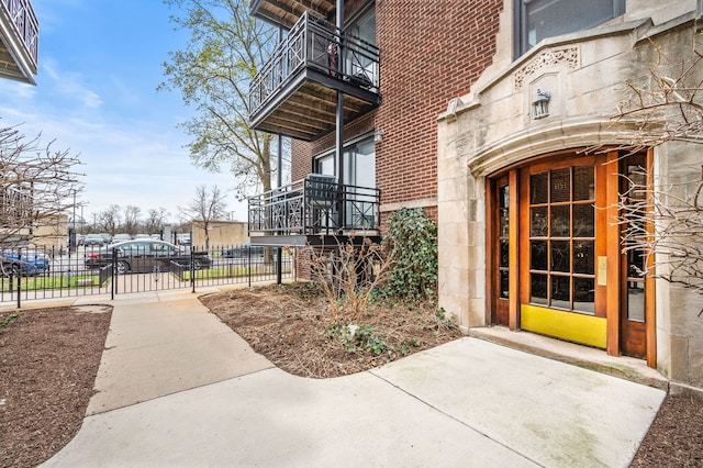 entrance to property with brick siding, fence, a gate, and a balcony