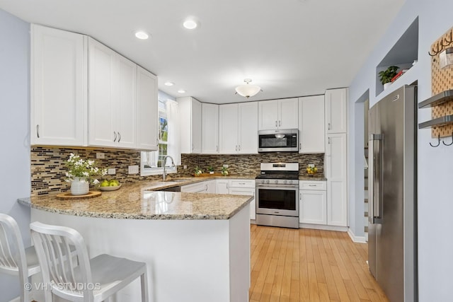 69 N Idlewild Ave, Mundelein, IL 60060 - kitchen featuring stainless steel appliances, a peninsula, a sink, backsplash, and white cabinetry