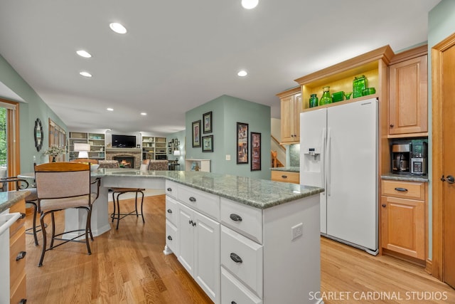 645 Rosewood Dr, West Chicago, IL 60185 - kitchen with white fridge with ice dispenser, light wood-type flooring, a warm lit fireplace, recessed lighting, and a kitchen island