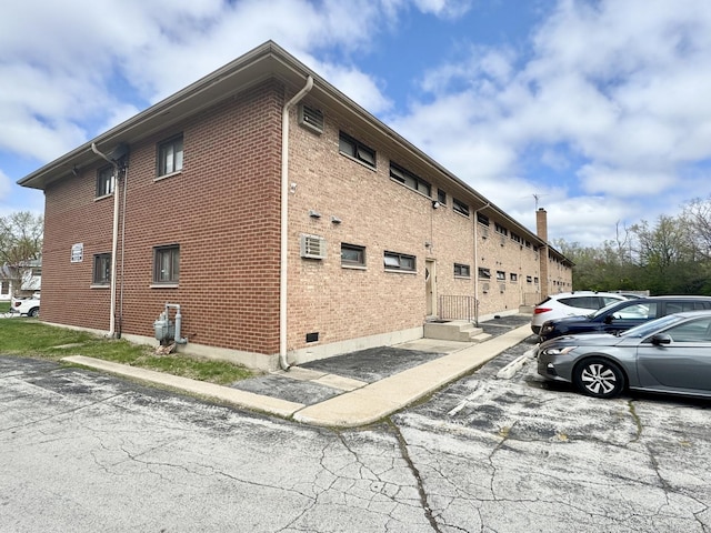 553 N Carroll Pkwy Unit 1-D, Glenwood, IL 60425 - view of side of home featuring uncovered parking, brick siding, and a wall mounted air conditioner
