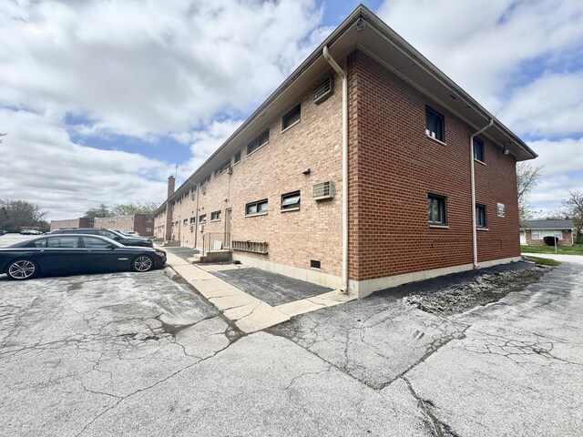view of side of home featuring brick siding and uncovered parking