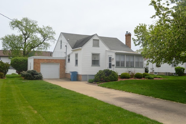 view of front facade featuring a chimney, a front lawn, a garage, and driveway