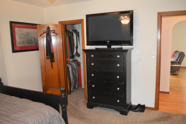 bedroom with a spacious closet, carpet floors, arched walkways, baseboards, and a closet