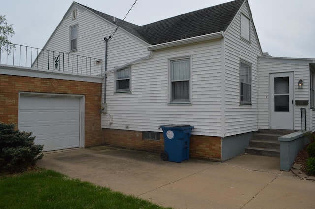 back of house featuring driveway, a shingled roof, and an attached garage