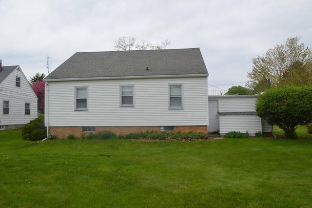 back of property with a lawn and roof with shingles