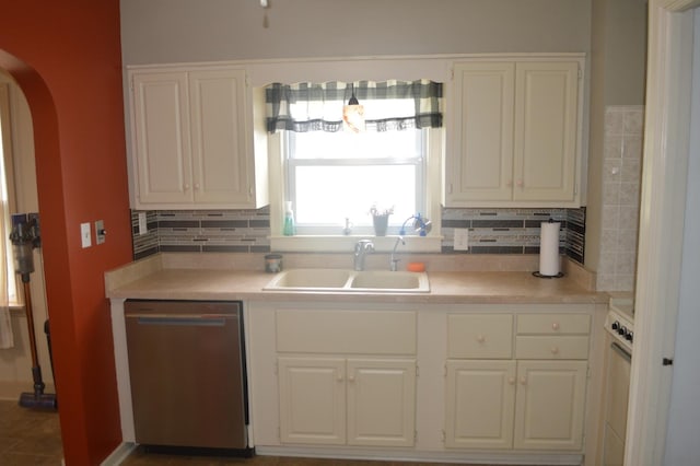 kitchen with dishwasher, a sink, arched walkways, white cabinetry, and light countertops