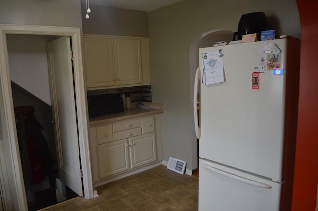 kitchen with freestanding refrigerator, light countertops, tasteful backsplash, and arched walkways