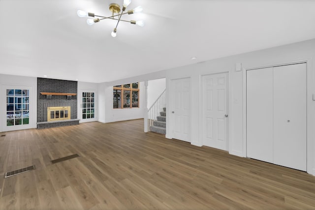 17247 Lakebrook Dr, Orland Park, IL 60467 - unfurnished living room featuring a notable chandelier, a brick fireplace, stairs, wood finished floors, and visible vents