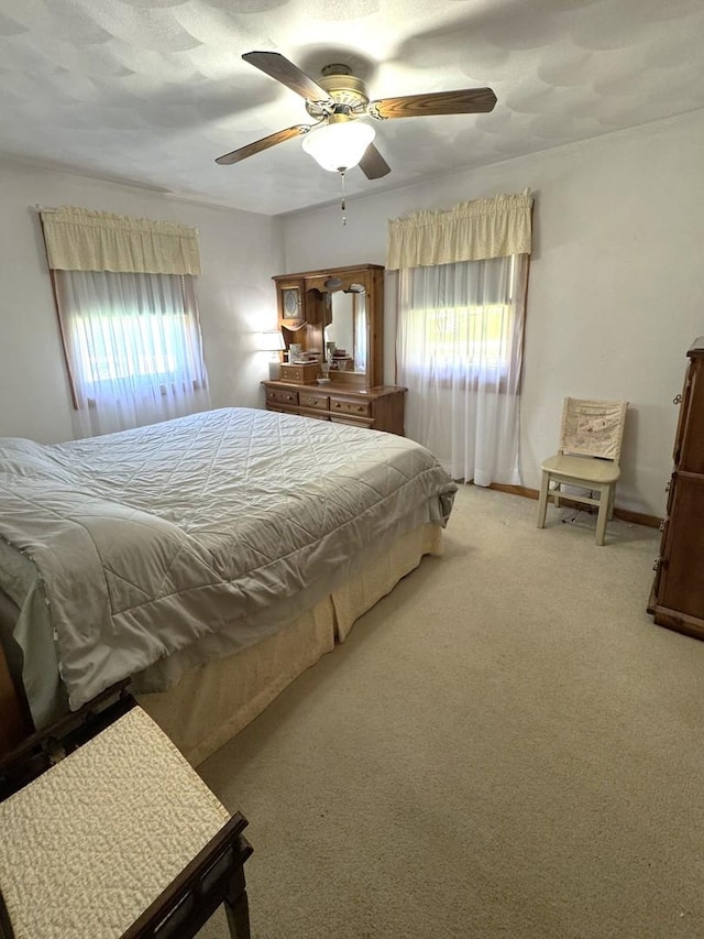 bedroom with light colored carpet, a ceiling fan, and baseboards