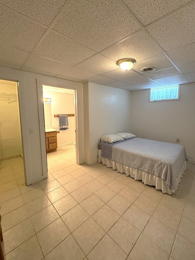 bedroom with light tile patterned floors, a drop ceiling, and visible vents